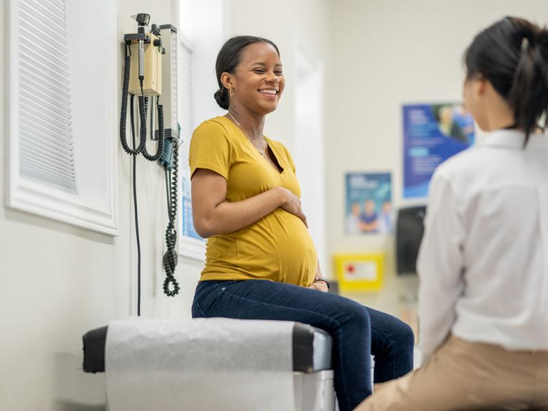 Smiling pregnant patient on an exam table in a doctors office
