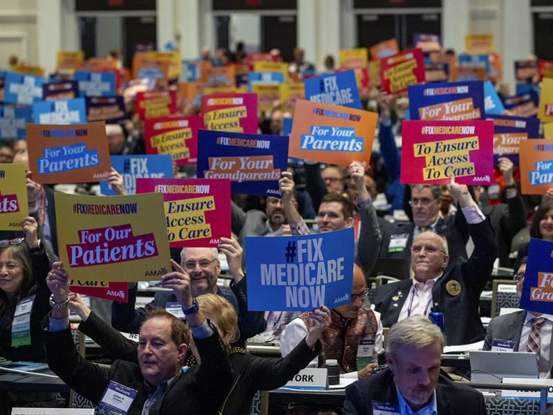 Delegates at the 2023 Interim Meeting of HOD hold "Fix Medicare Now" signs