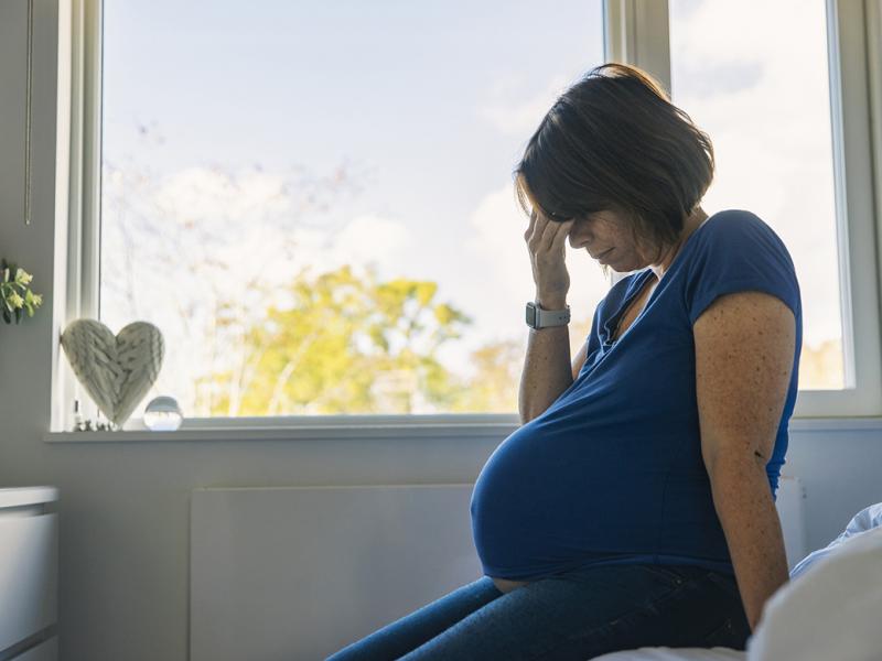 Pregnant woman with hand over eyes