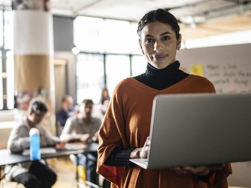 Smiling young woman holding a laptop