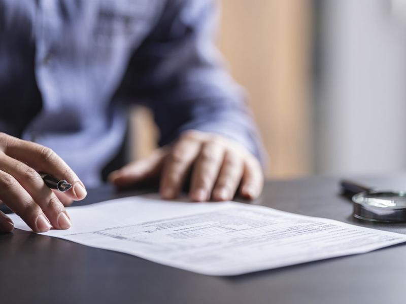 Hand holding pen over a contract