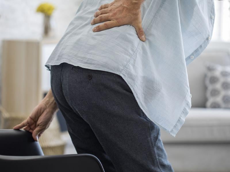 Person clenched over with hand on back