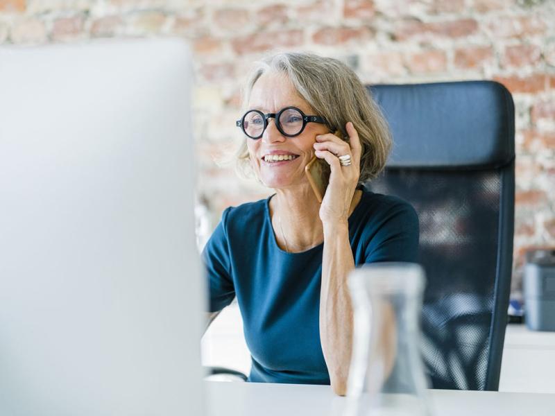 Senior businesswoman at her desk using cell phone