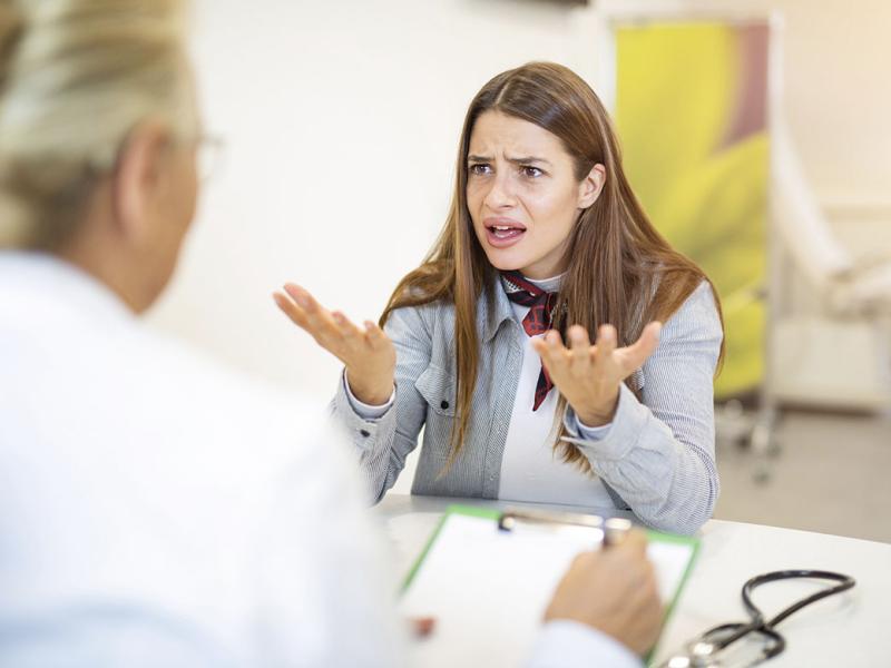 Perturbed patient holds up hands during an appointment