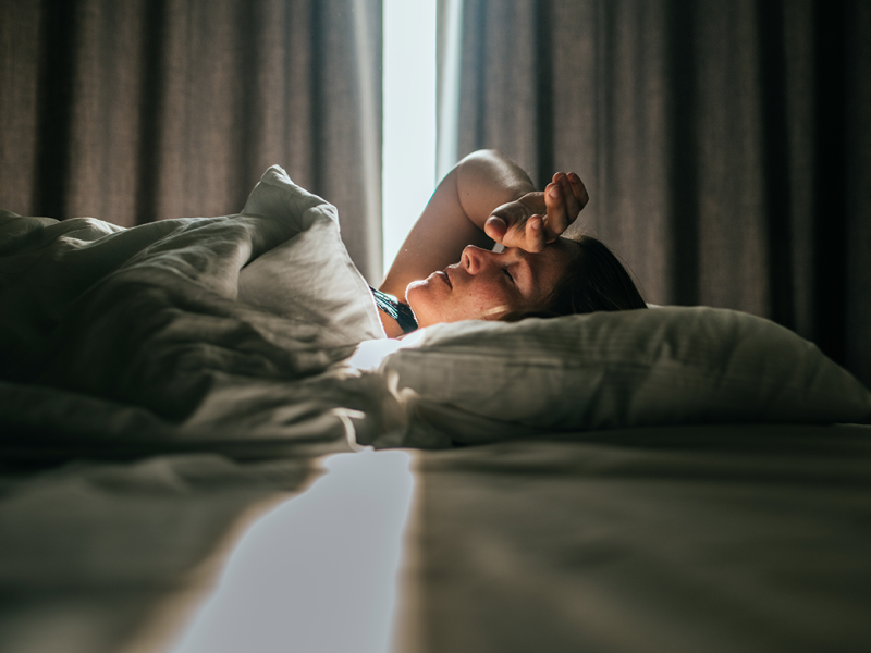 Person in bed, hand over forehead