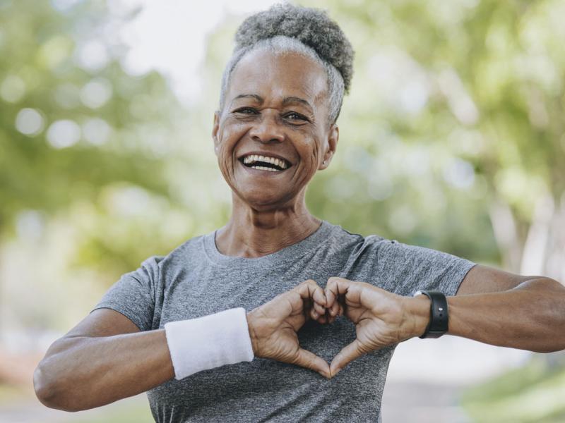 Smiling person makes a heart symbol with hands