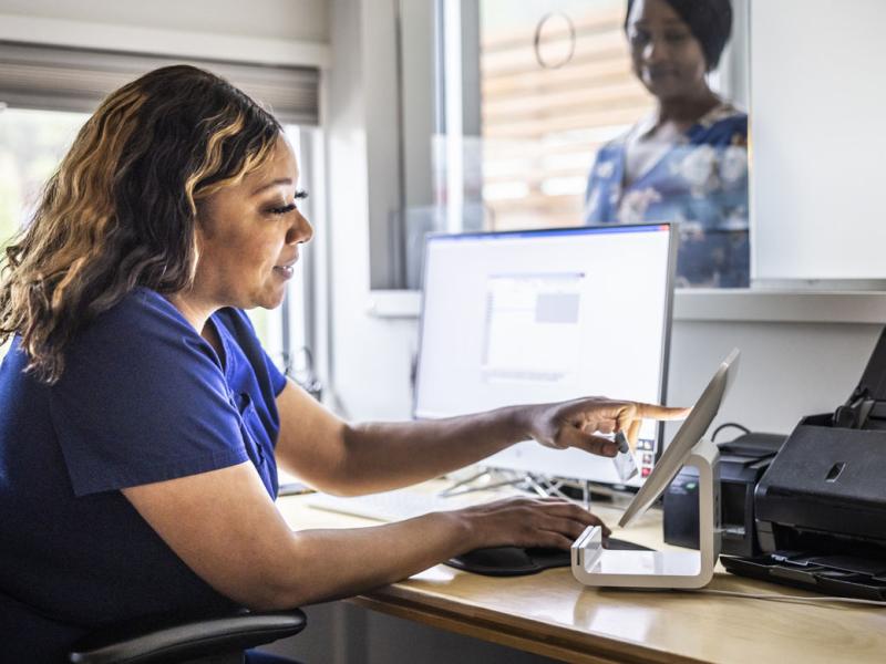 Health care worker accepting payment from patient at reception desk in doctor's office