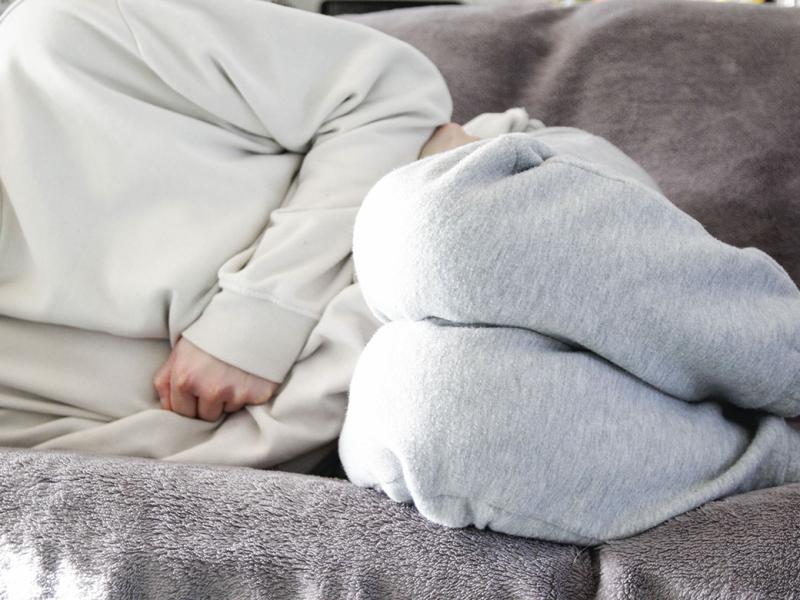 Woman on couch clutches midsection