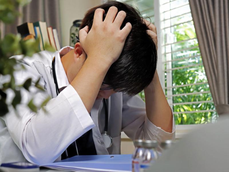 Physician with head in hands