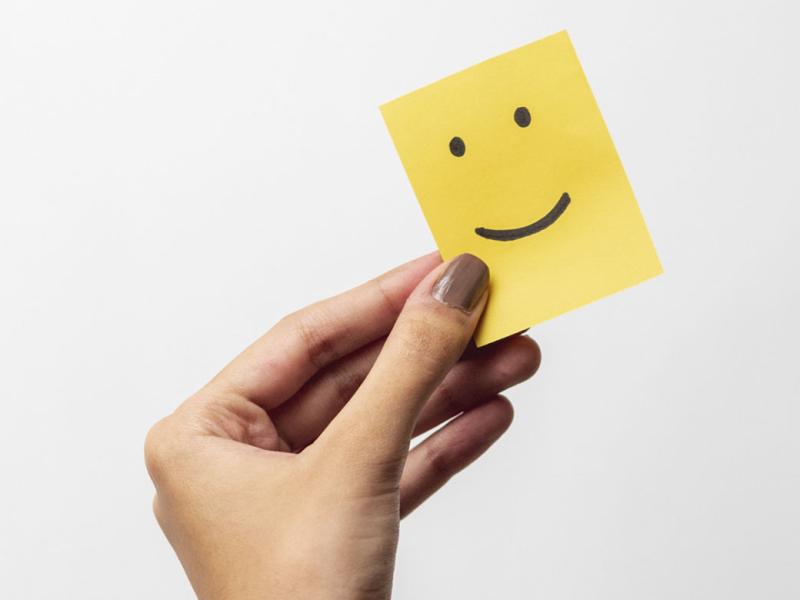 Hand holds a piece of paper with a smiley face