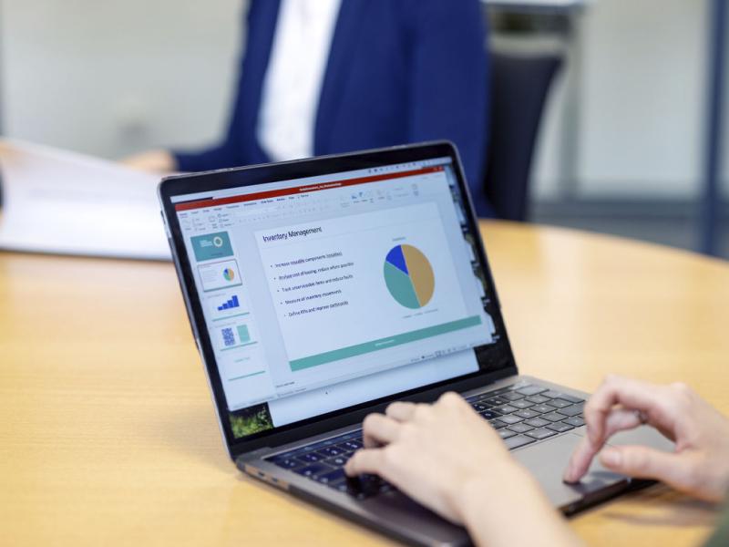 Person preparing business report on a laptop sitting at office