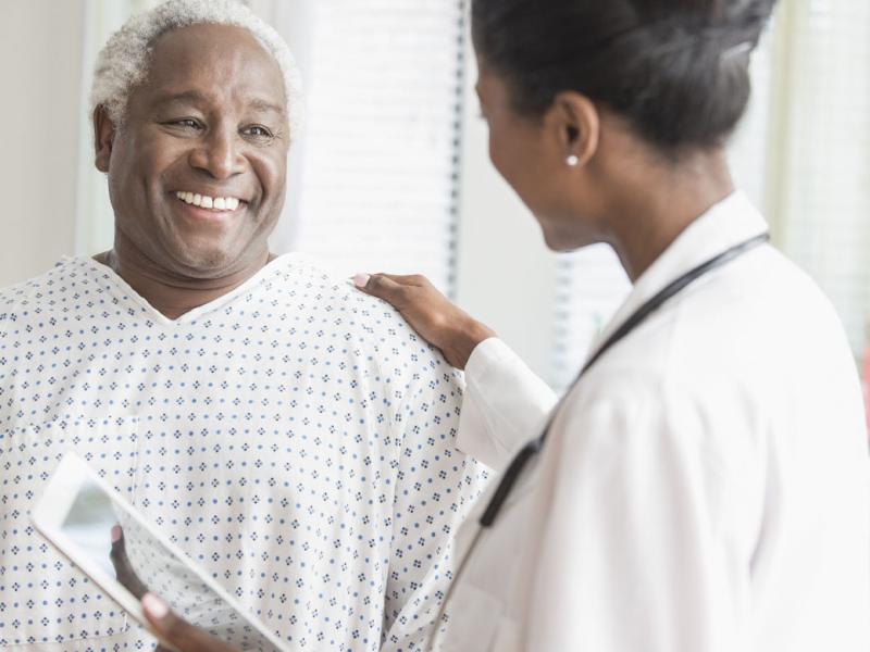 Physician places hand on smiling patient's shoulder