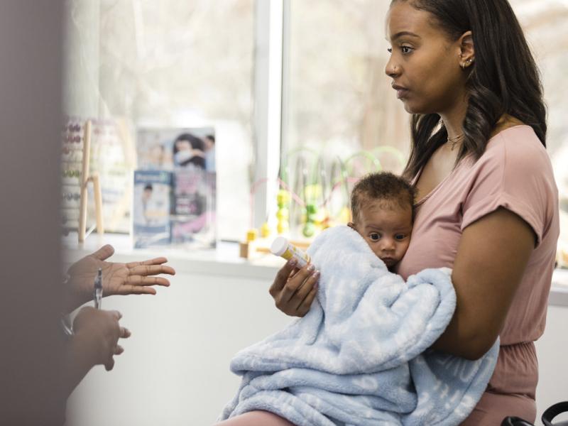 Mom holding baby gets medicine from doctor