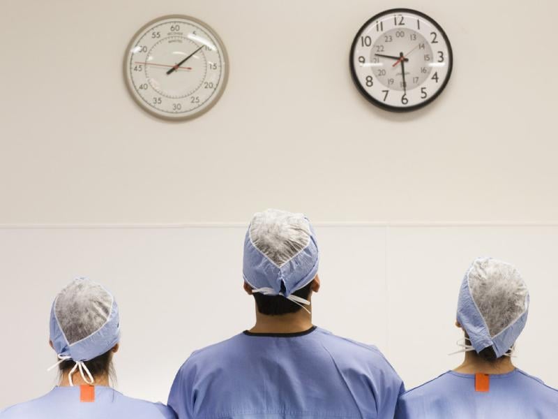 Three physicians facing toward two clocks on a wall