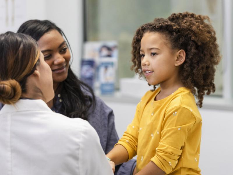 Young patient in a doctor's appointment while smiling parent looks on