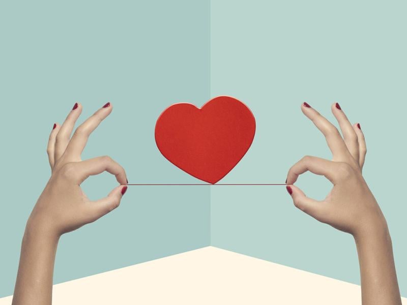 Heart balanced on a string held by two hands