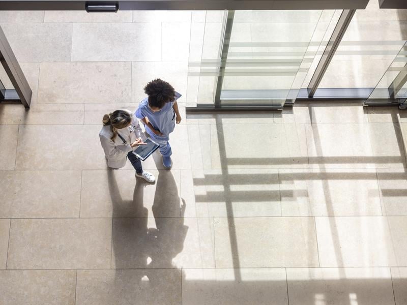 Doctor looking at test results with a colleague on a digital tablet while walking at the hospital