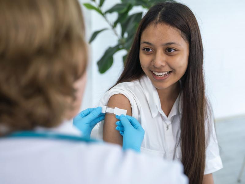Adhesive bandage applied to upper arm of smiling young patient