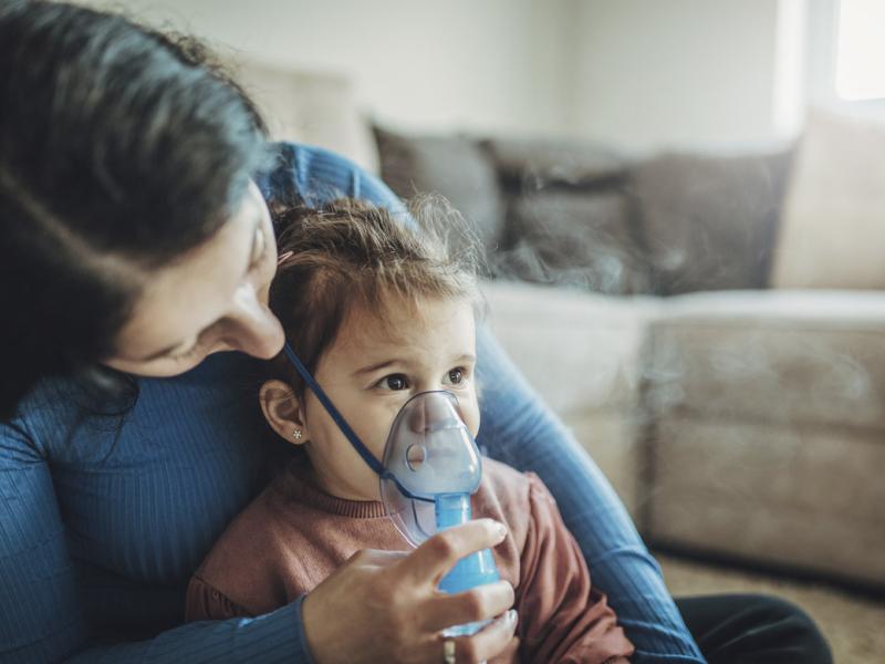 Parent helps young child use inhaler