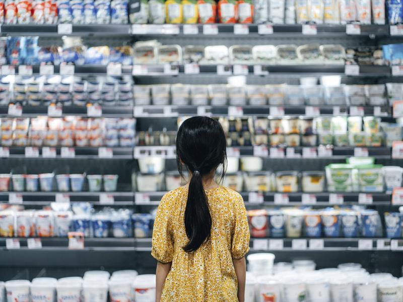 Child standing in front of a shelf full of fresh products in a supermarket