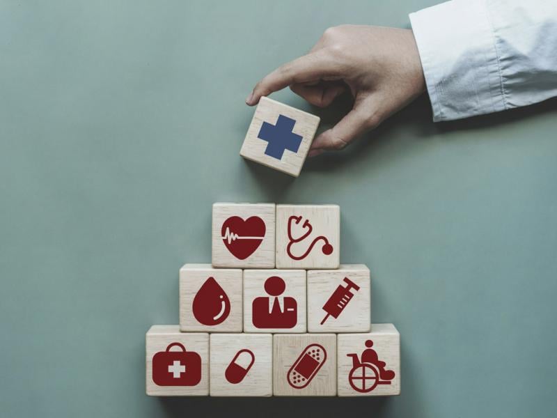 Hand stacking blocks with health care icons