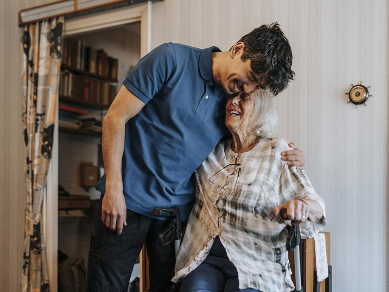 Smiling caregiver embraces older smiling patient