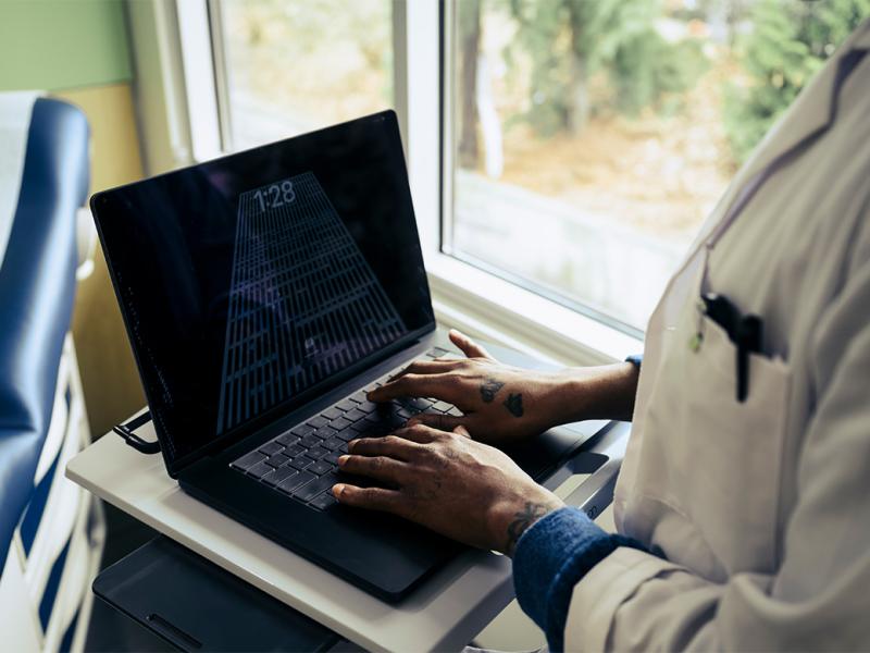 Health care worker types on a laptop