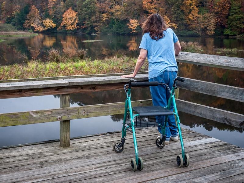 Person with a walker stands on a dock