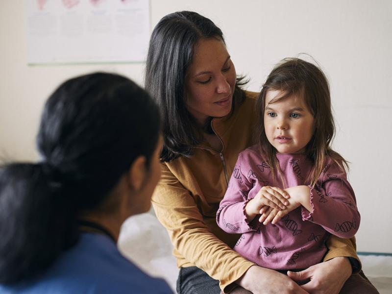Parent holds young child during doctor's appointment