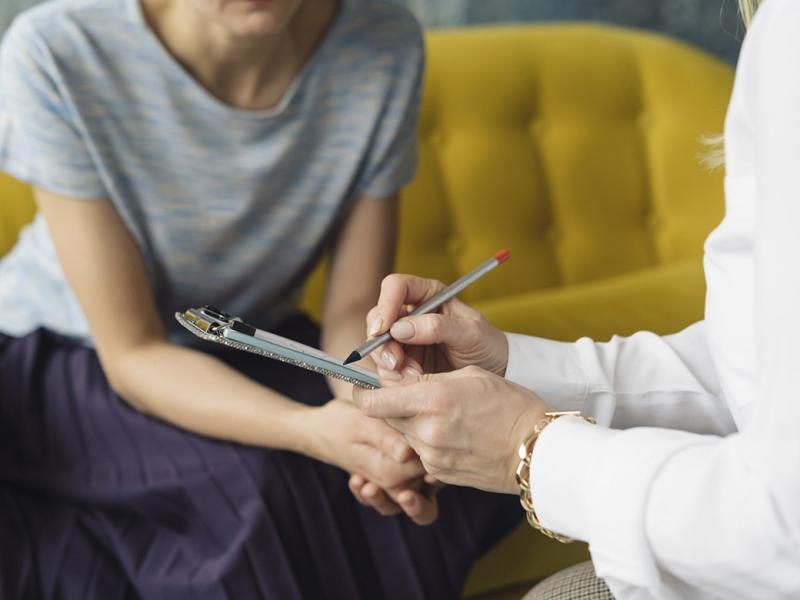 Physician writing notes while talking to patient