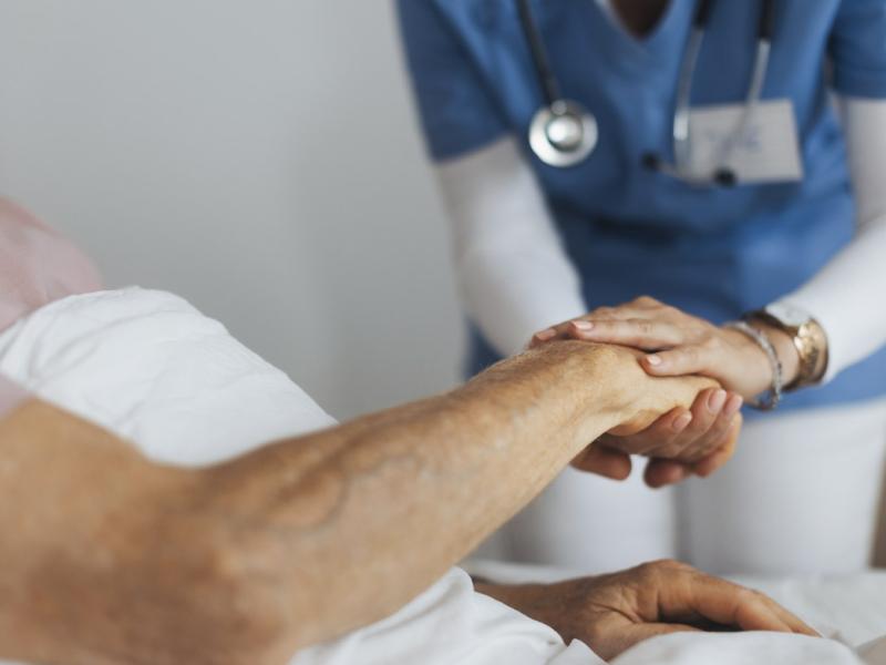 Healthcare worker holds a patient's hand