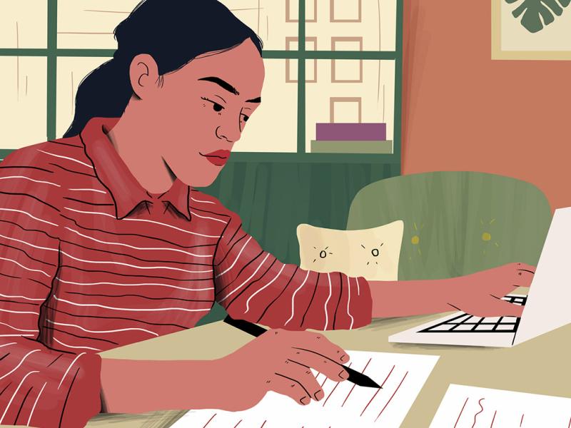 Person examining document sitting with laptop at table 