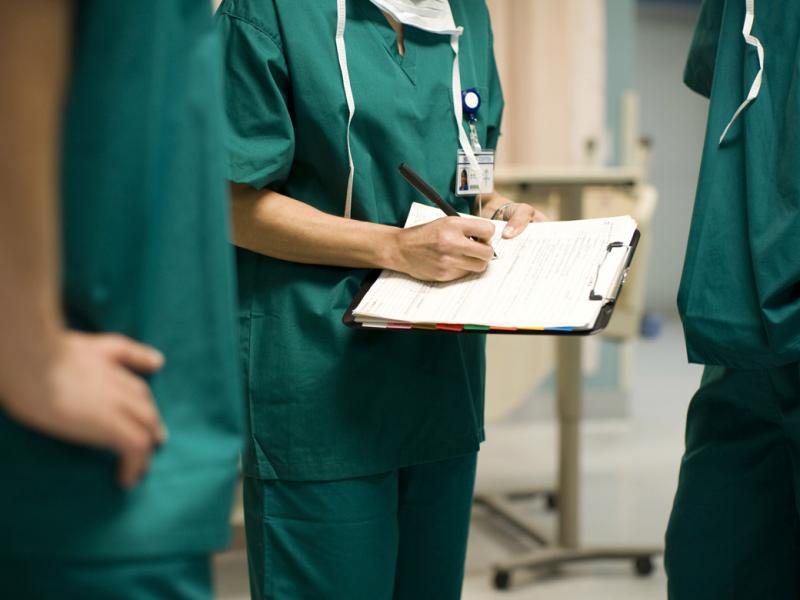 Physician writes on a clipboard