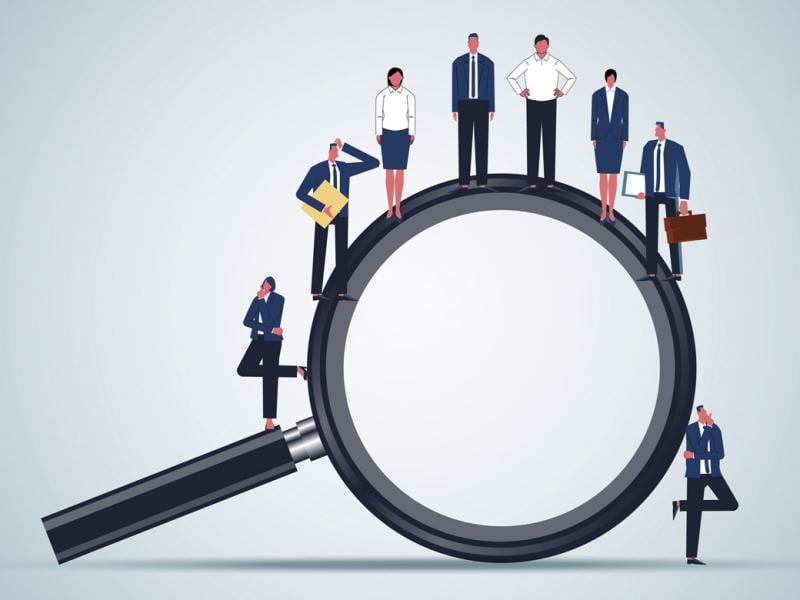 Figures stand on a giant magnifying glass