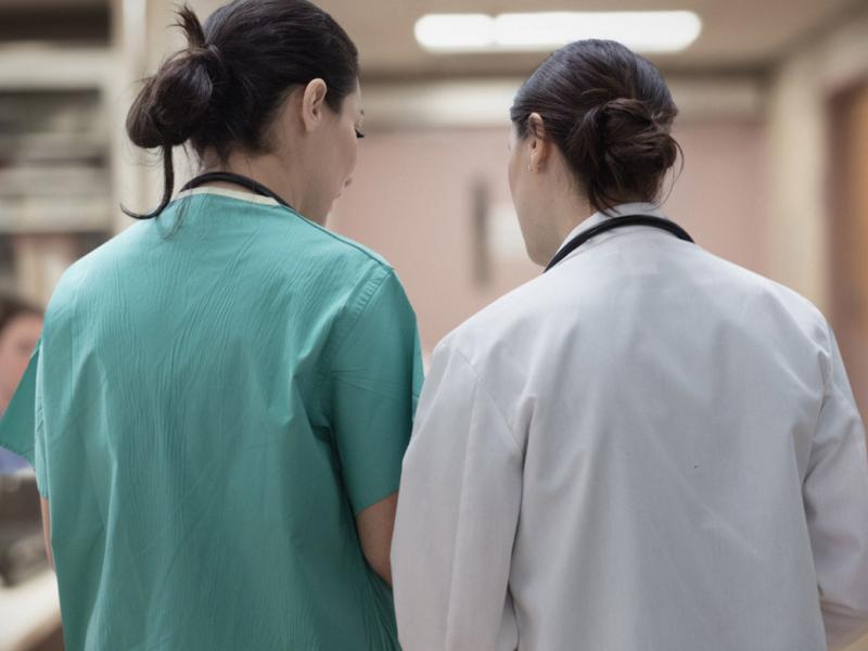 Two healthcare workers talking in hospital hallway