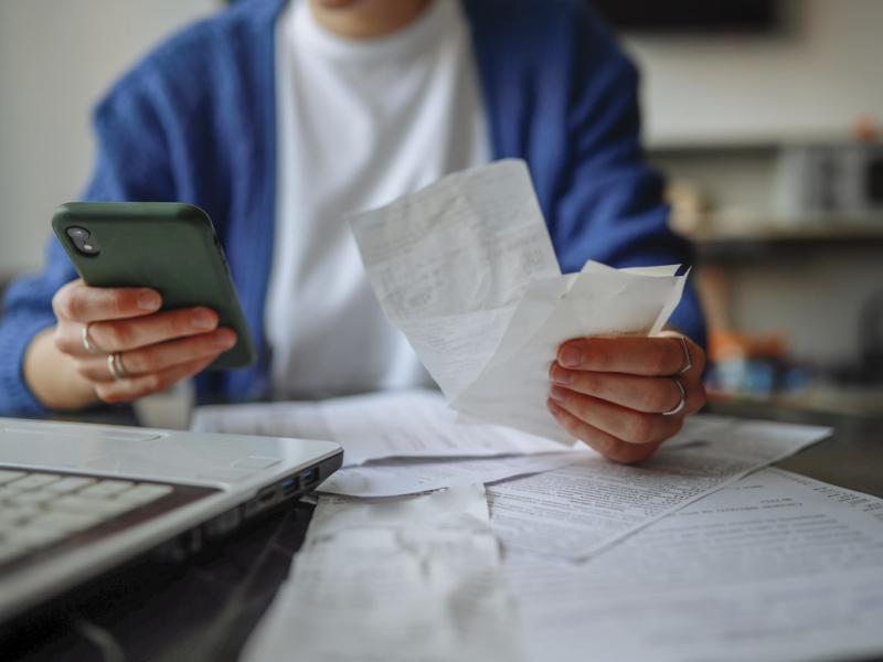 Person holds receipts in one hand and smartphone in another hand