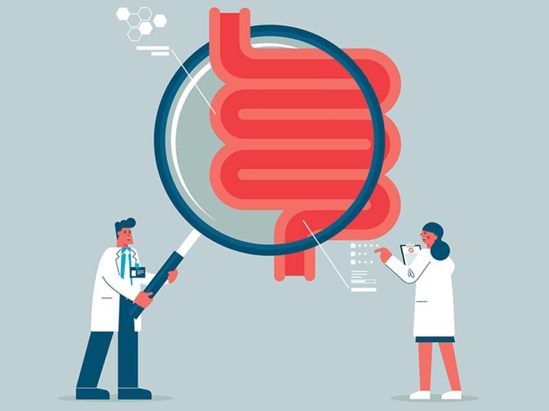 Team of doctors hold giant magnifying glass over human digestive system