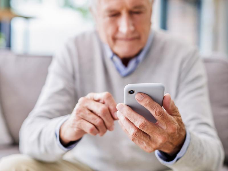 Senior man using a phone at a clinic