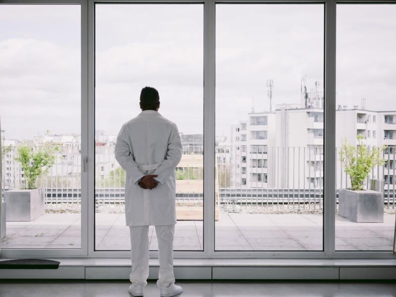 Physician stands in front of a window