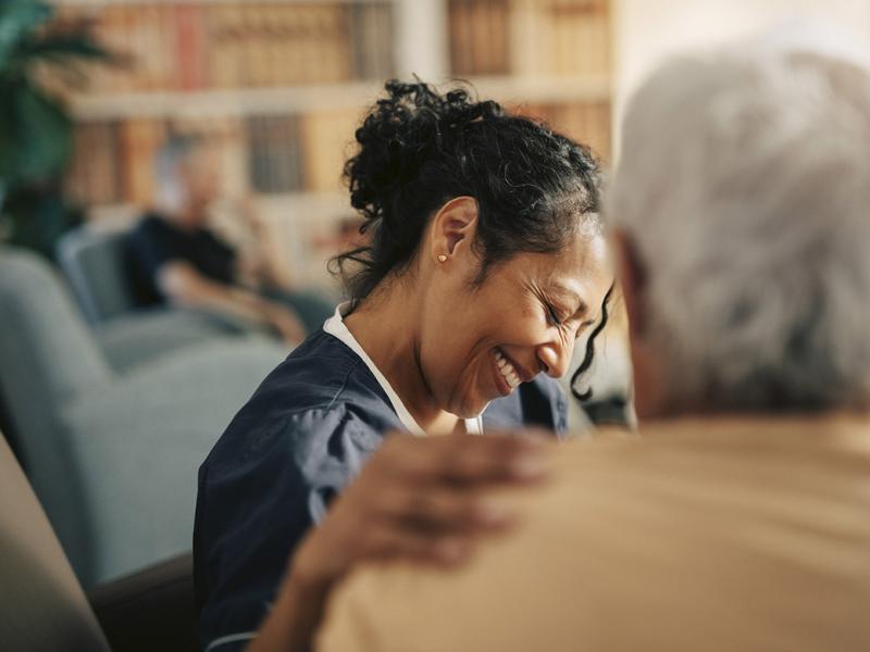 Smiling healthcare worker with hand on patient's shoulder