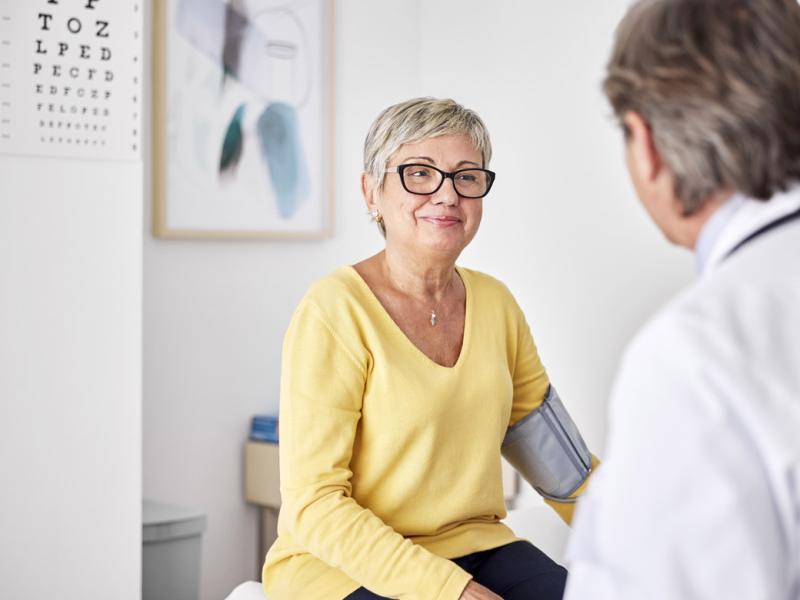 Smiling patient wearing blood pressure belt during appointment