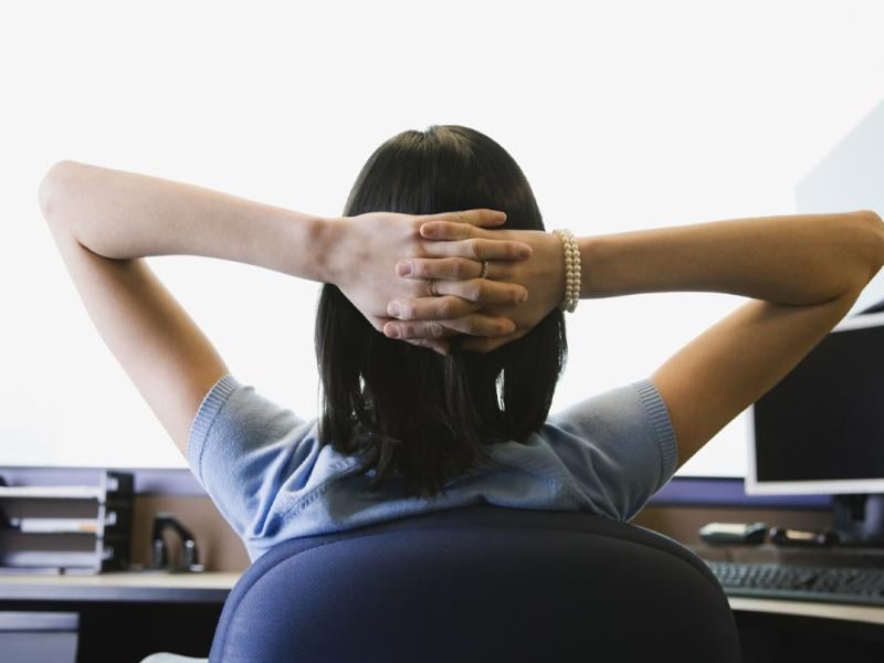 Person sits at a desk with hands clasped behind head