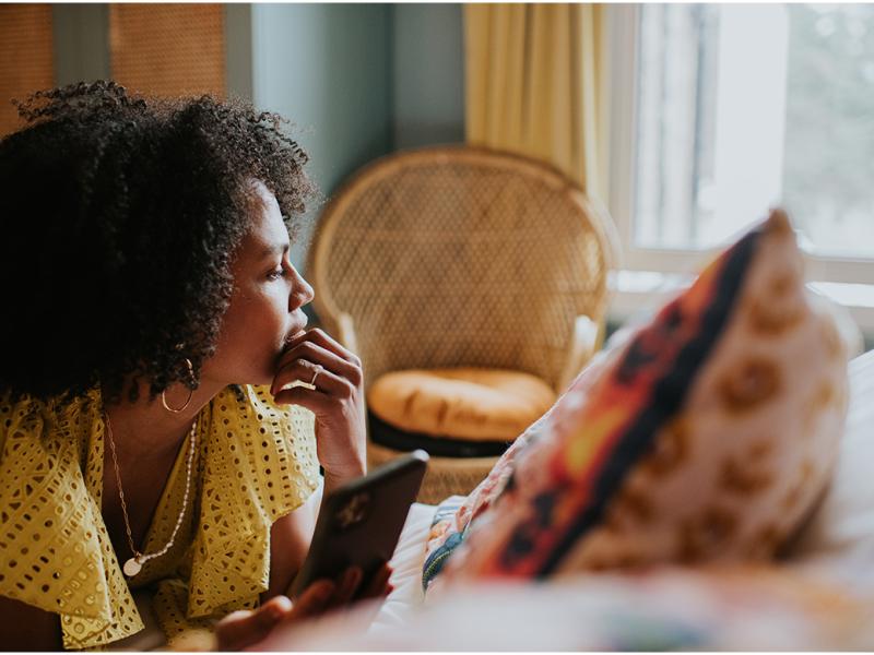 Woman looks off into the distance, smartphone in hand
