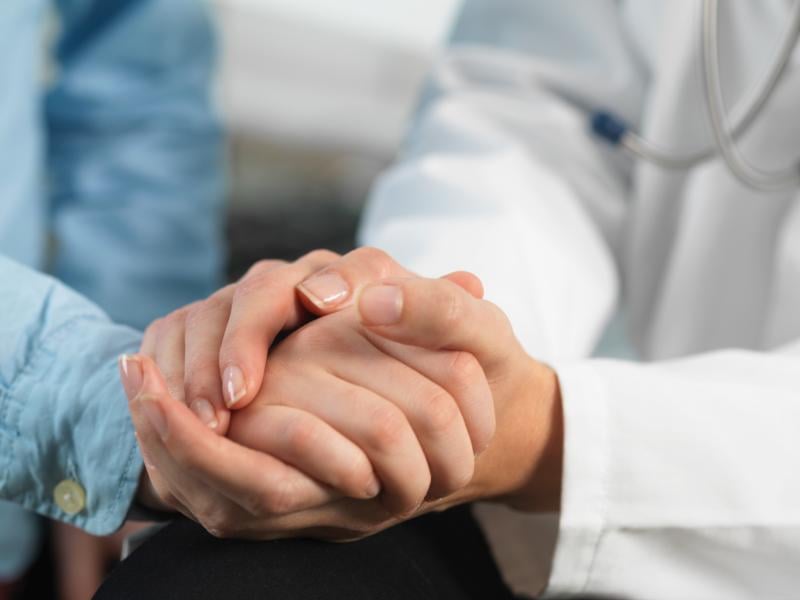 Physician holds patient hand