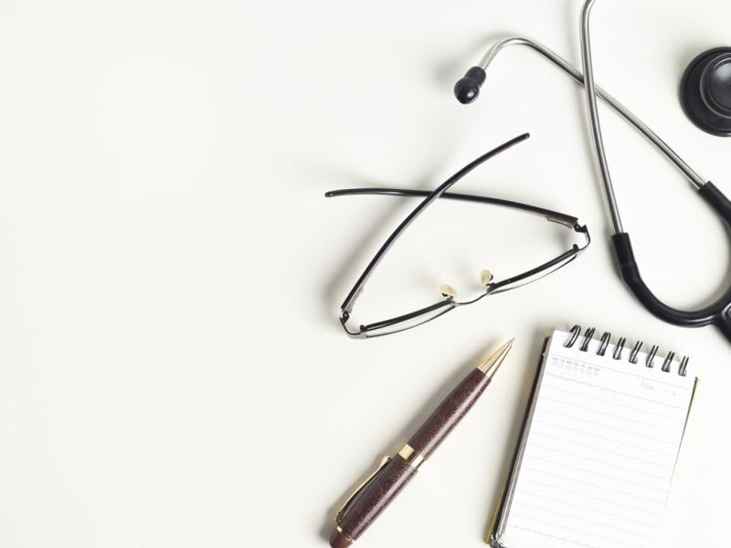 Stethoscope, glasses, pen and paper