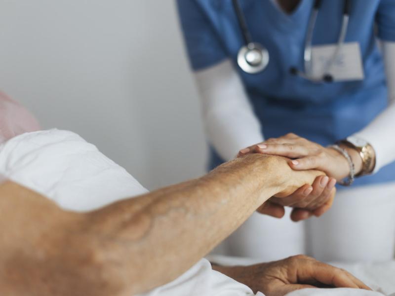 Healthcare worker holds patient's hand