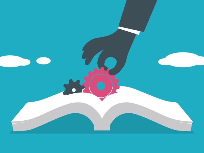 Hand pulls a gear from an open book