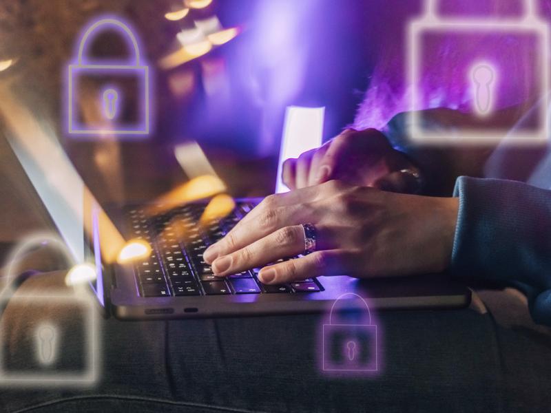 Hands on a laptop surrounded by IT security lock symbols