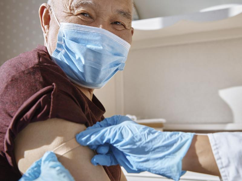 Gloved hands apply bandage to upper arm of smiling patient