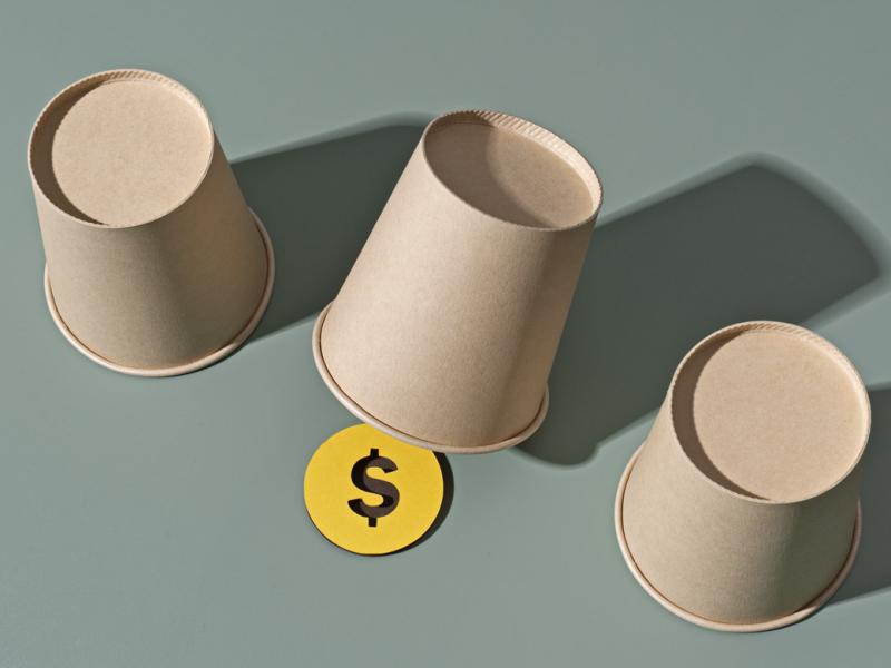 Three cups, one with a dollar sign underneath it